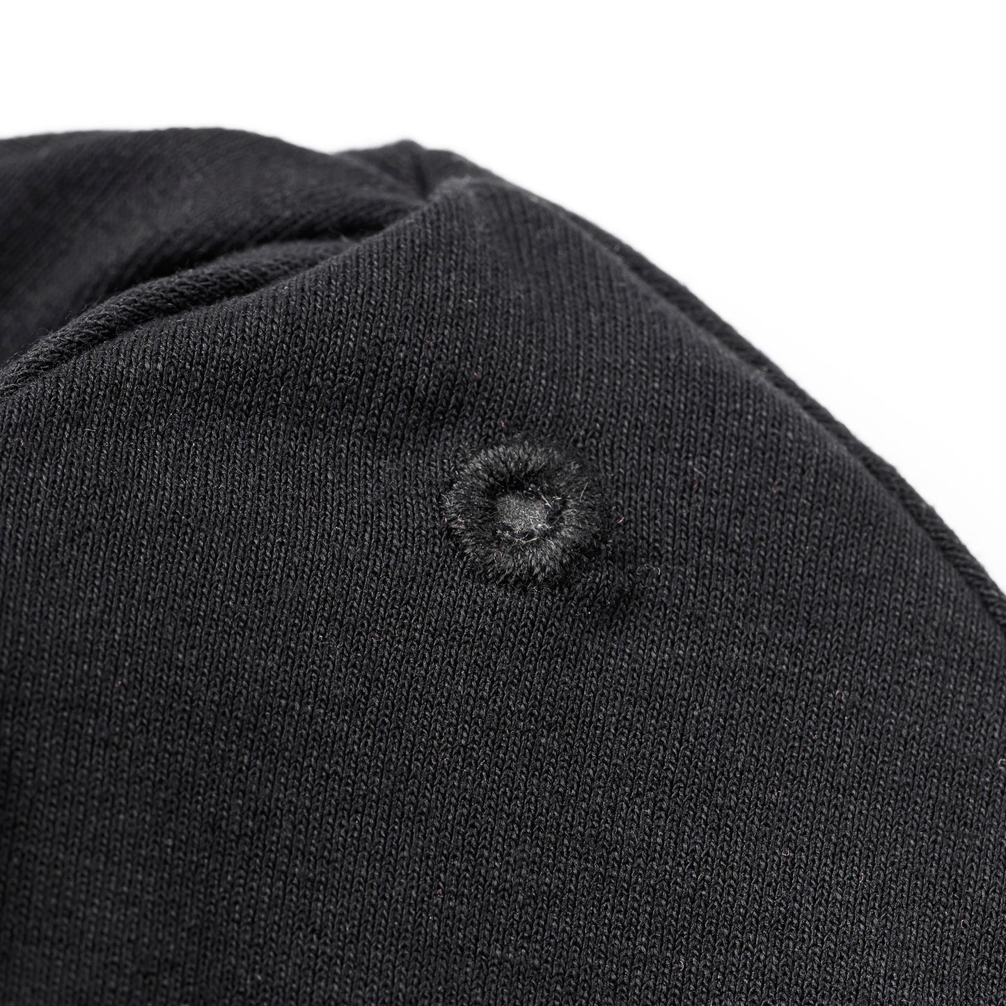 Detailaufnahme der verstärkten Öse auf der schwarzen OBIXS® Handtuchmütze für den verstellbaren Verschluss.