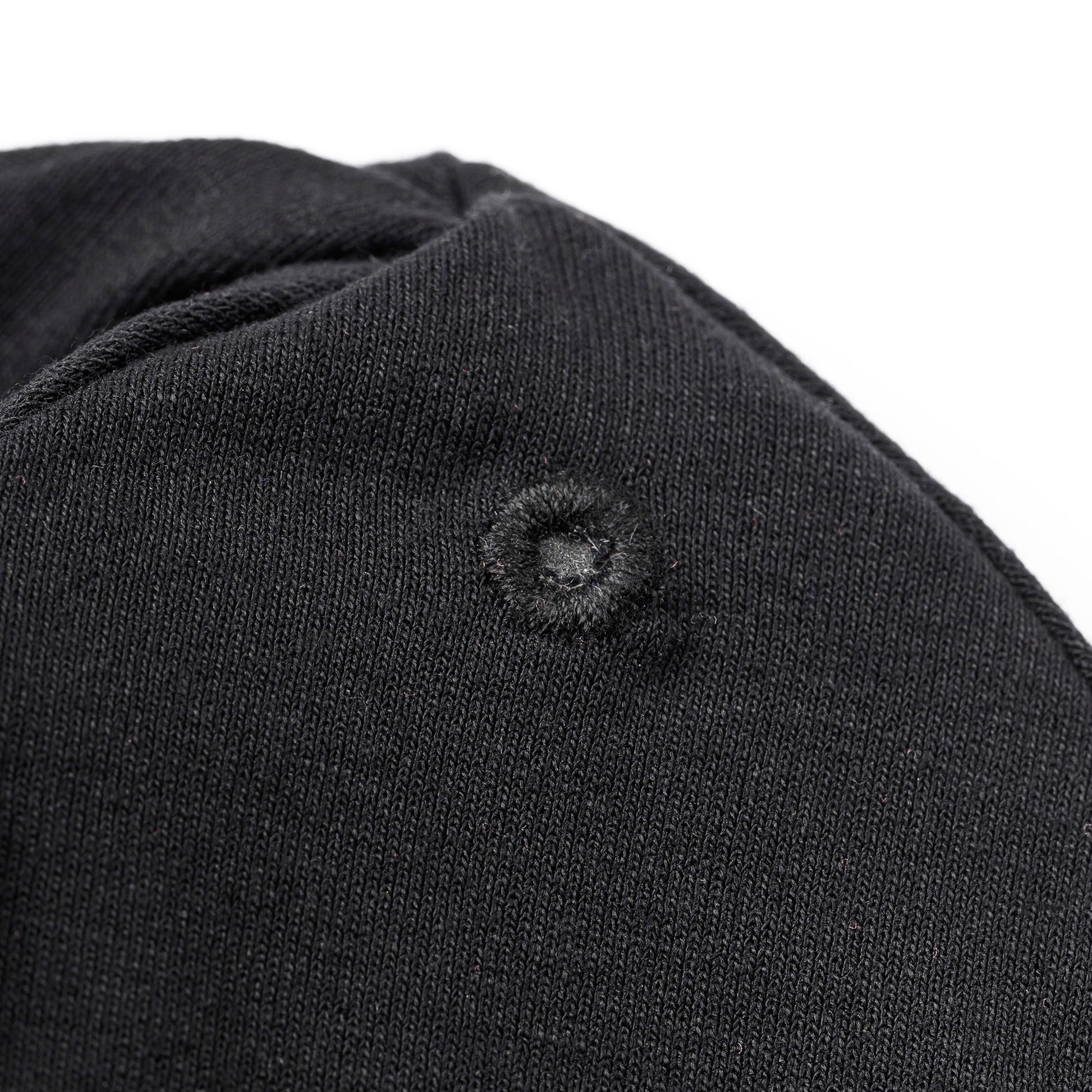 Detailaufnahme der verstärkten Öse auf der schwarzen OBIXS® Handtuchmütze für den verstellbaren Verschluss.